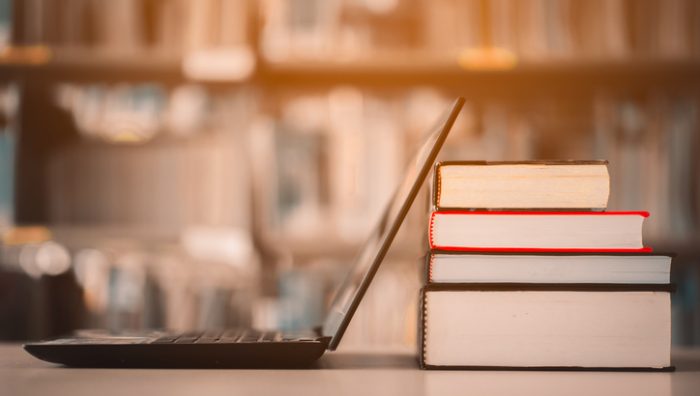 Bookshelves and laptops are placed on the library desk.E-learning class and e-book digital technology Bookshelves and laptops are placed on the library desk.E-learning class and e-book digital technology
